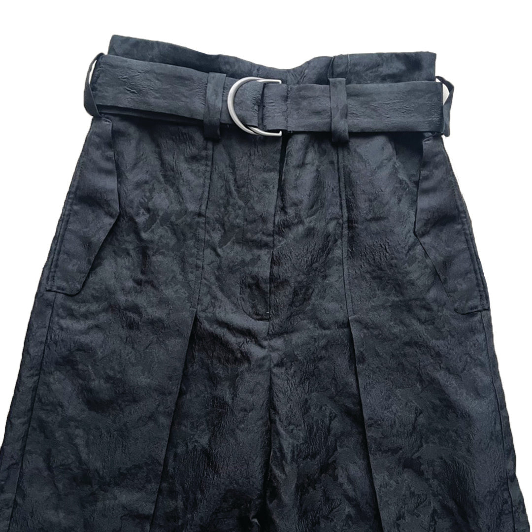 A close-up image of Katia Pleated Hakama Pants by Maison Lilli featuring a wide belt with a silver buckle, displayed against a white background.